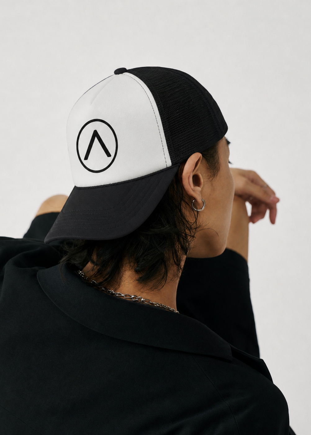 Person wearing a black and white cap with a logo on a plain background